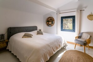 A bedroom with a large bed, a chair, a window, and a wall-mounted shelf. - Villa Margot, stunning pool, beach 500 m (Agde)