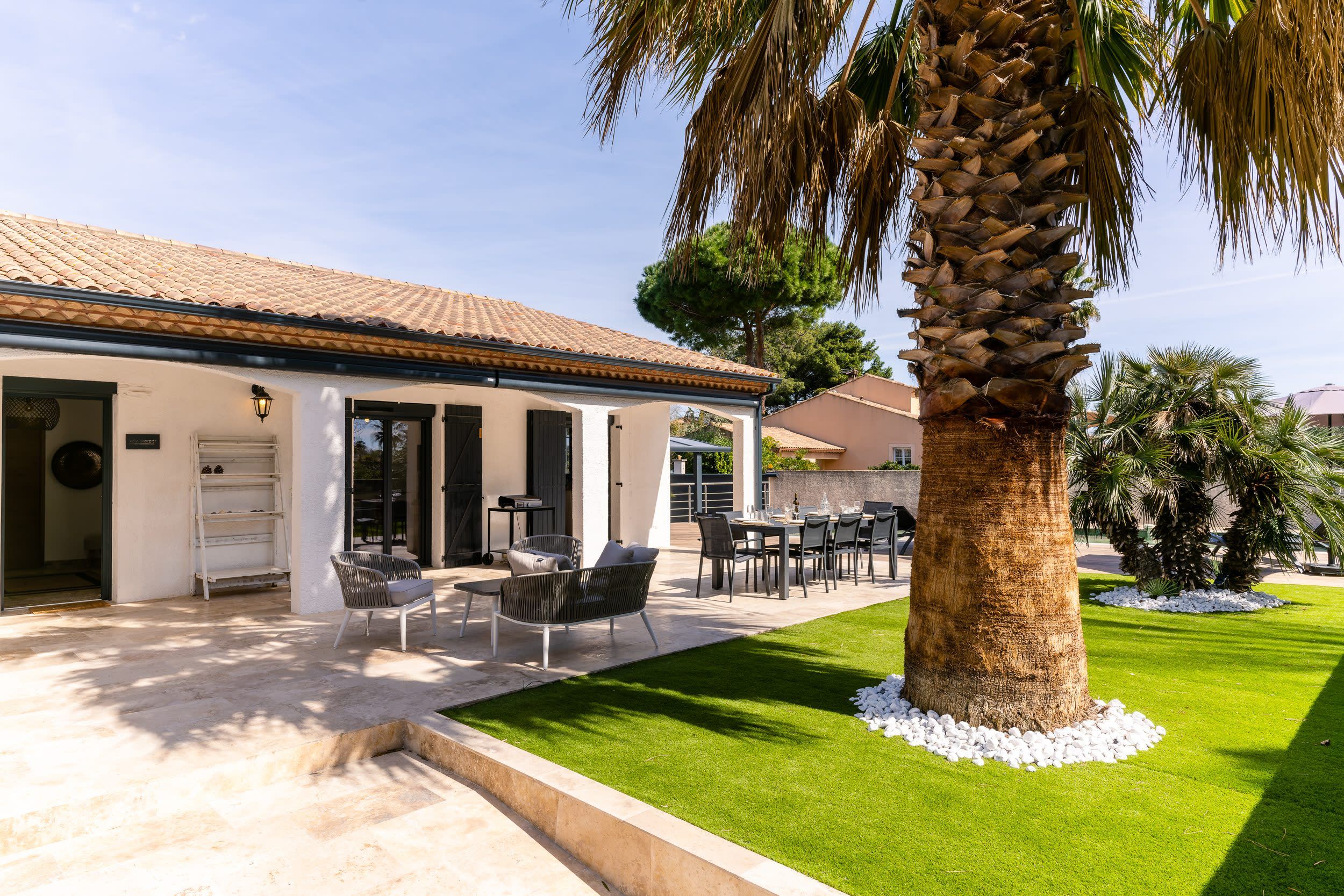 Une maison avec un patio, un espace salon extérieur et un palmier.