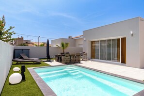 A modern outdoor swimming pool area with a lounge chair, a small table, and a palm tree. - Villa Juxta Maré, Beach 500 m Away (Sérignan)