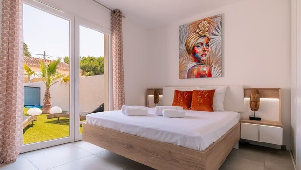 A modern bedroom with a large bed, a painting on the wall, and a view of the outdoors. - Villa Juxta Maré, Beach 500 m Away (Sérignan)