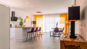 A modern kitchen with a central island, purple chairs, and a dining table with orange curtains. - Villa Juxta Maré, Beach 500 m Away (Sérignan)