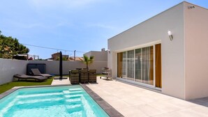 A modern outdoor pool area with a clear blue pool, lounge chairs, and a patio with a table and chairs. - Villa Juxta Maré, Beach 500 m Away (Sérignan)