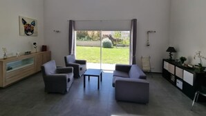 A modern living room with a sofa set, a coffee table, and a large sliding glass door leading to a garden. - Villa - Le Castellet (Le Castellet)