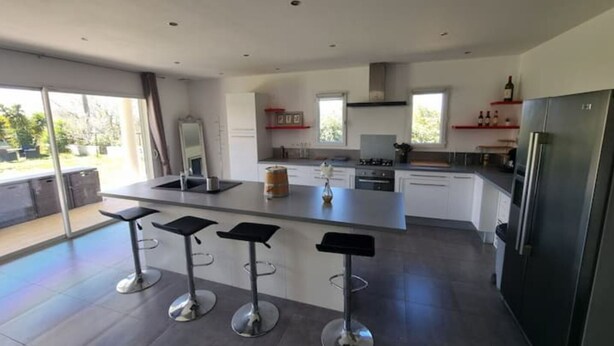 A modern kitchen with a central island, bar stools, and a large refrigerator. - Villa - Le Castellet (Le Castellet)