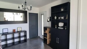 A modern interior with a dark wood floor, a black console table with framed pictures, a chandelier, and a black cabinet with 'HOME' on the door. - Villa - Le Castellet (Le Castellet)