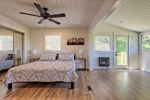 Une chambre avec un grand lit, un ventilateur de plafond et une fenêtre équipée de stores.