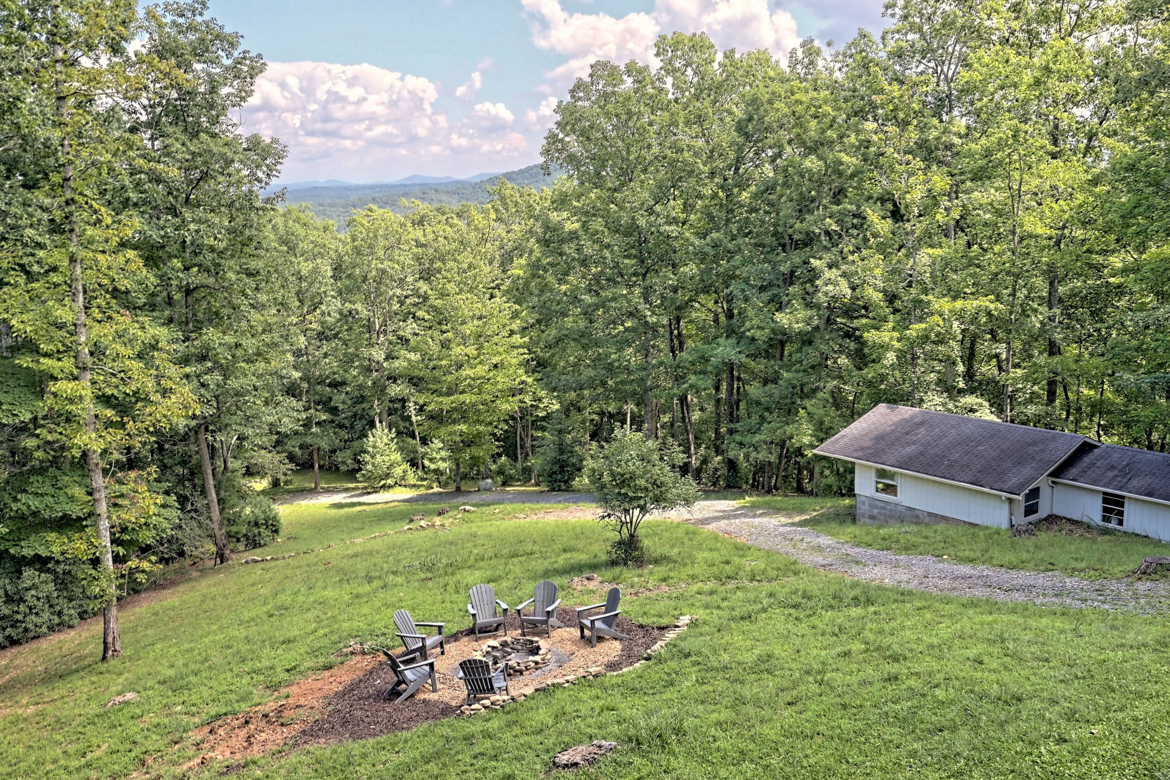 Une cabane avec un foyer et des fauteuils Adirondack, située dans une zone boisée.