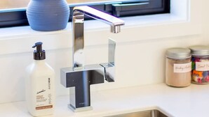 A kitchen with a stainless steel sink, a blue vase with pink flowers, and a bottle of hand soap. - Gateway to Hagley Park - 2 Bed w/Carpark (Christchurch)