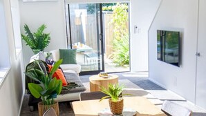 A modern dining area with a wooden table and chairs, surrounded by a carpeted floor. - Gateway to Hagley Park - 2 Bed w/Carpark (Christchurch)