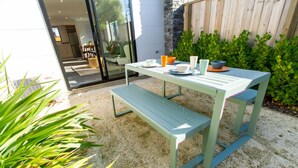 An outdoor patio with a table and benches, surrounded by greenery and a wooden fence. - Gateway to Hagley Park - 2 Bed w/Carpark (Christchurch)