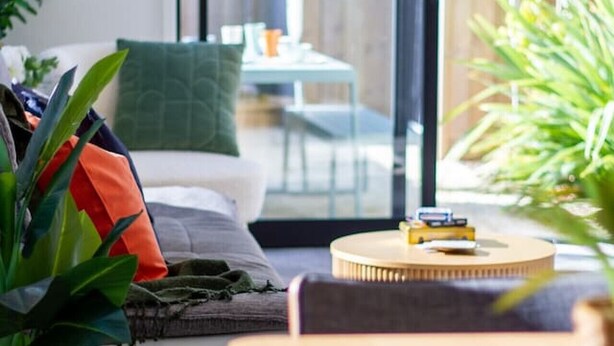 A modern living room with a sofa, a coffee table, and a dining table. - Gateway to Hagley Park - 2 Bed w/Carpark (Christchurch)