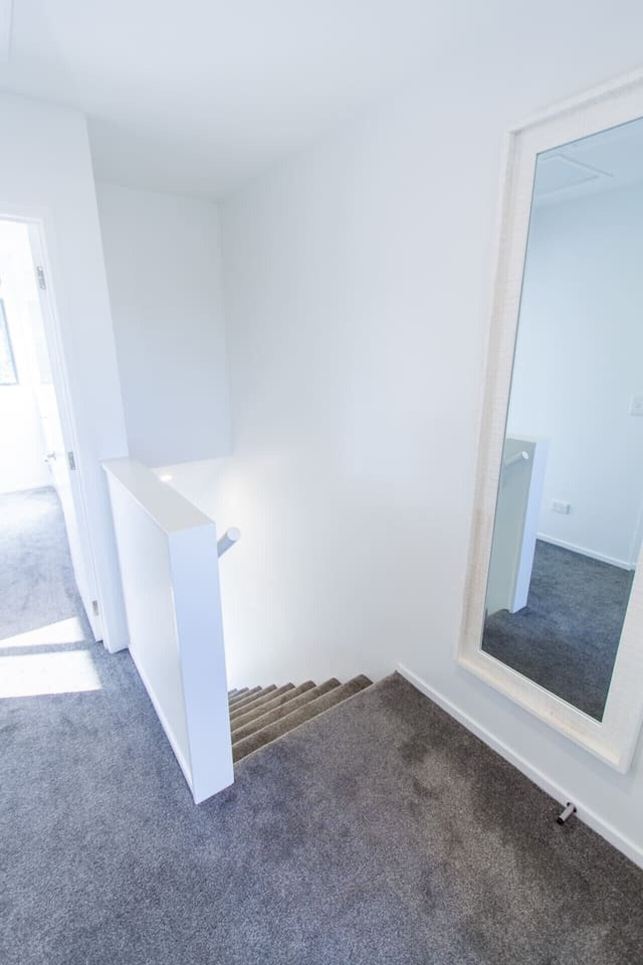 Una habitación con pared blanca, un ventanal grande y piso alfombrado.