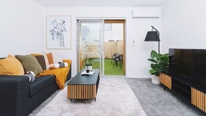 A modern living room with a sofa, coffee table, and TV stand. - 1 Bed Central City Fringe Deluxe w/Carpark (Christchurch)