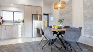 A modern kitchen with a large window, a dining area with a table and chairs, and a hanging light fixture.