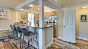 A kitchen with a central island, bar stools, a refrigerator, and a door with a sign. - Walk to Lake: Osage Beach Home w/ Grill! (Osage Beach)