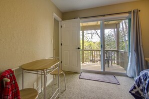 Relax in a comfortable space with a carpeted floor, small table, and chair, and step out to a balcony with a view of the surrounding trees.