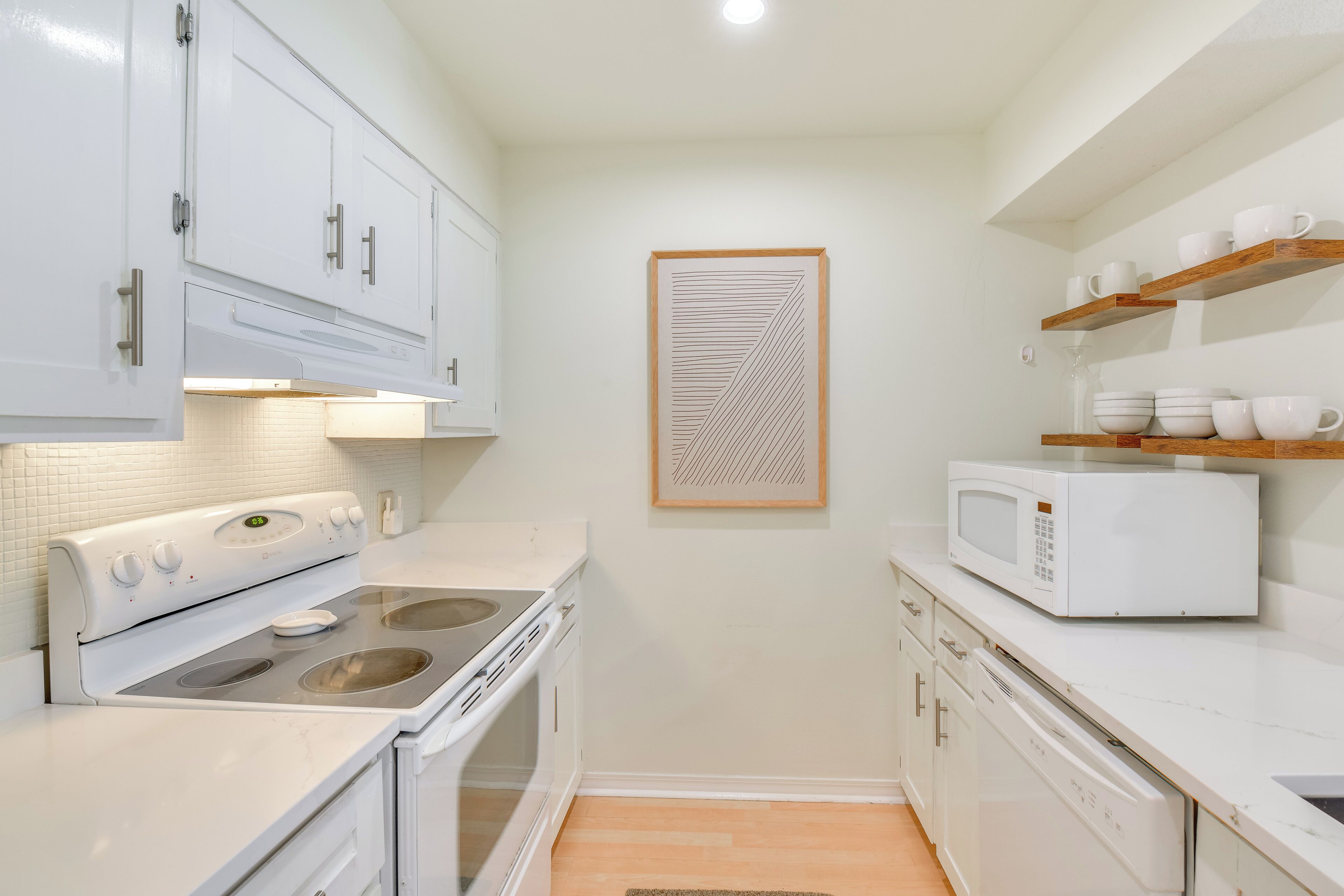 Una cocina compacta con armarios blancos, un microondas y una estufa.