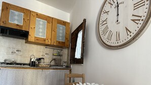 Una cucina con mobili in legno, una grande sveglia a parete e un tavolo da pranzo con sedie.