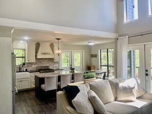 A modern kitchen with white cabinets, a central island, and a dining area with a table and chairs.