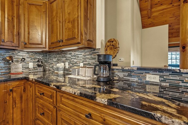 A kitchen with wooden cabinets, a tiled backsplash, and a granite countertop. - Crooked Feather @ River Ridge Awaits You! (Boone)