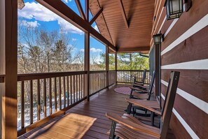 A wooden deck with benches and a railing, overlooking a natural landscape.