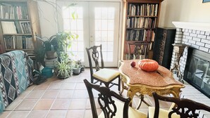 Een eethoek met een tafel en stoelen, omringd door boekenkasten en potplanten.