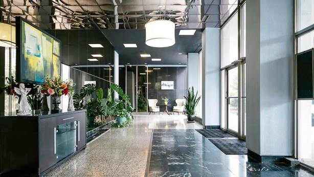 Un hall d’entrée moderne avec un comptoir d’accueil, des plantes en pot et un espace salon.