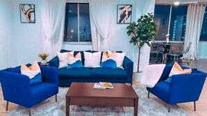 Un salon avec un canapé bleu, une table basse et une plante en pot.