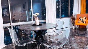 Un espace repas moderne avec une table ronde, des chaises transparentes et un vase rempli de fleurs.