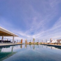 Una piscina al aire libre, sombrillas, sillones reclinables de piscina