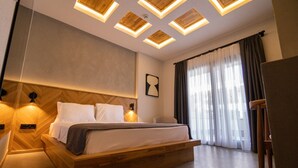 A modern hotel room with a wooden bed, built-in headboard, and a large window with curtains. - Leone Cunda Edition Otel (Ayvalik)