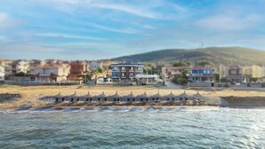 A coastal hotel with a beach view, a pool, and a mountain in the background. - Leone Cunda Edition Otel (Ayvalik)