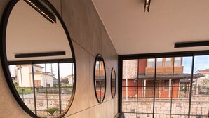 A modern interior with a long bench, round mirrors, and a view through large windows. - Leone Cunda Edition Otel (Ayvalik)