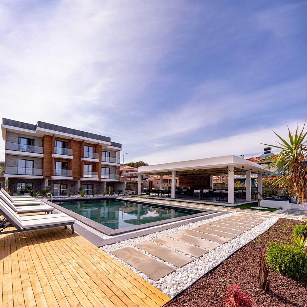 A modern hotel with a swimming pool, outdoor seating, and a covered area.