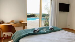 Un dormitorio con una cama grande, un escritorio y vistas a una piscina.