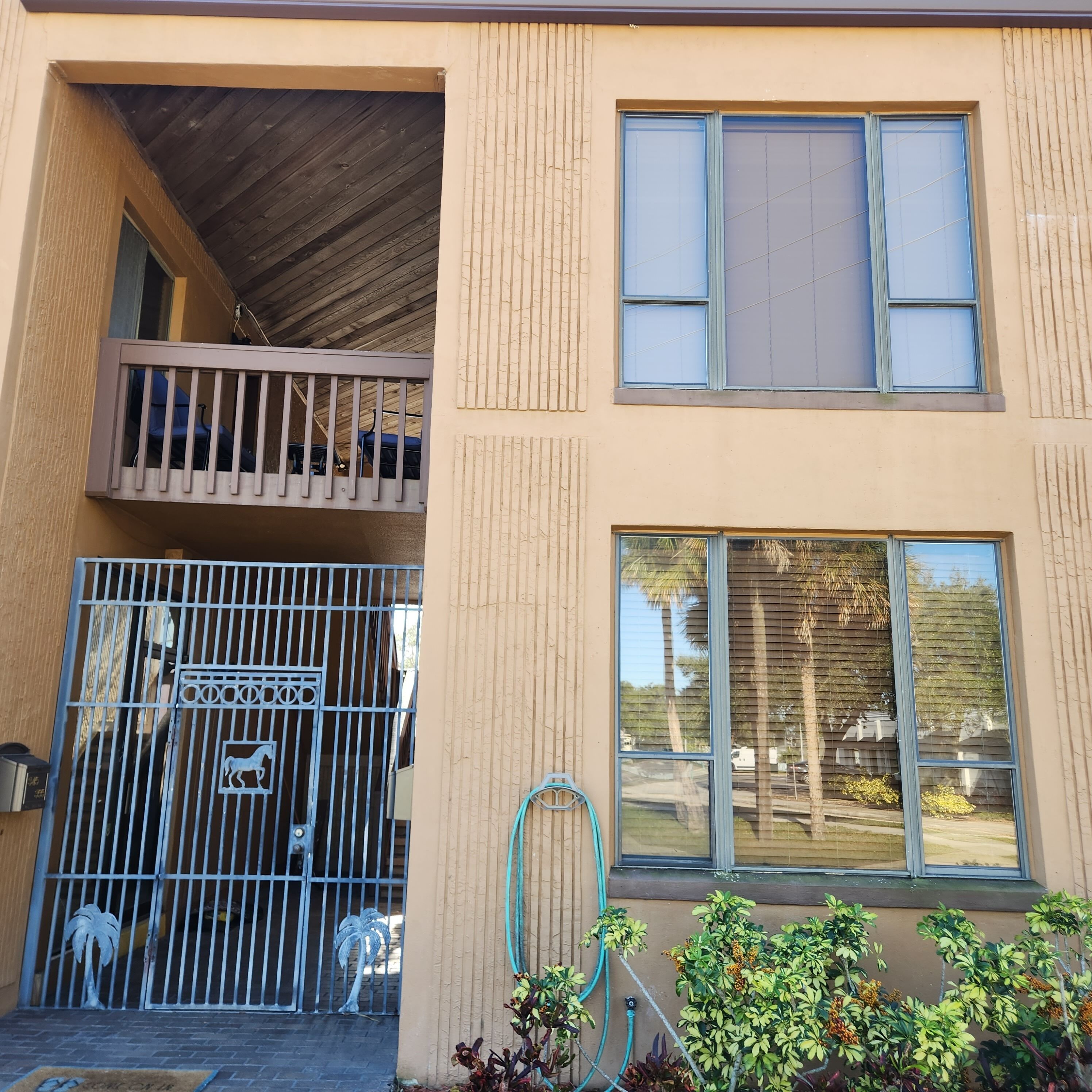 Een gebouw met twee verdiepingen, een balkon, een hekpoort en grote ramen.