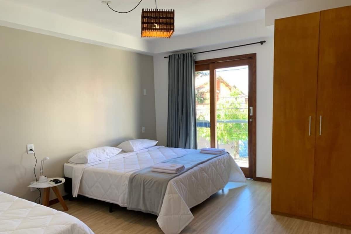 Une chambre à coucher comprenant un lit, une table de chevet, une armoire et une fenêtre avec des rideaux.
