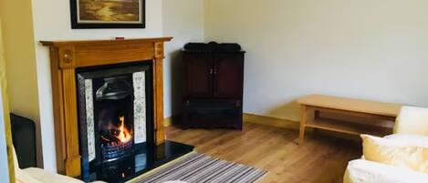 A living room with a fireplace, a sofa, a wooden bench, and a cabinet.