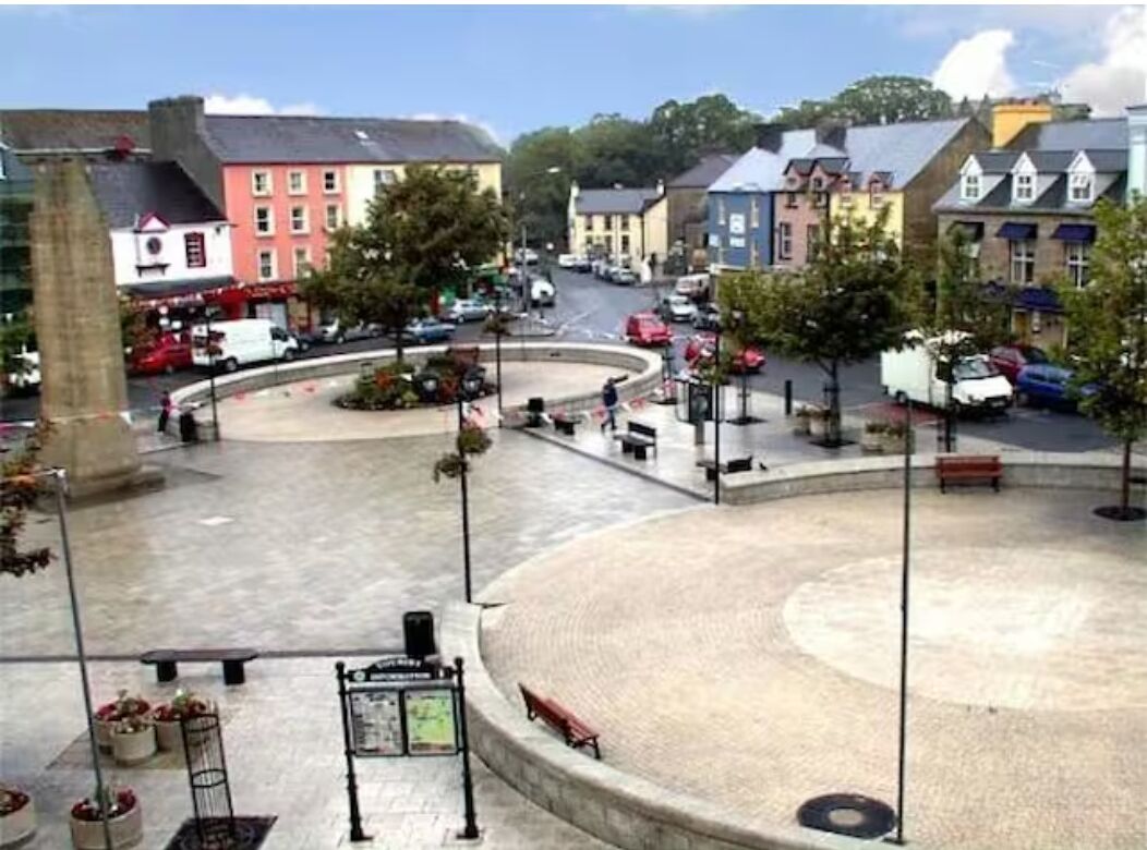 A roundabout with a central plaza, benches, and a signpost.