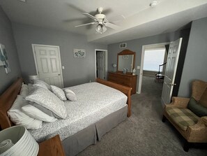 Ein Schlafzimmer mit Bett, Kommode, Stuhl und Deckenventilator.