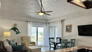 Ein Wohnzimmer mit Deckenventilator, einer Couch, einem Couchtisch und einem Fernseher.