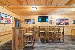 A wooden interior with a bar area, multiple seating options, and wall-mounted artwork. - Double Down Lodge | 5BR Group Getaway, Hot Tub & Game Room Near Old Man's Cave (Logan)