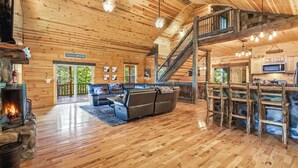 Amplia sala de estar con chimenea, una escalera y una zona de cocina.