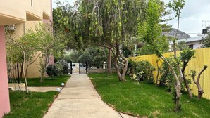 A residential driveway leading to a gated entrance, surrounded by well-maintained grass and trees. - Mediterranean Sea Top Floor (Kantanos-Selino)