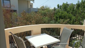 A balcony with a table and two chairs, surrounded by a metal railing. - Mediterranean Sea Top Floor (Kantanos-Selino)