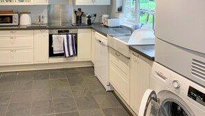 A modern kitchen with white cabinetry, a built-in oven, a dishwasher, and a Bosch washing machine.