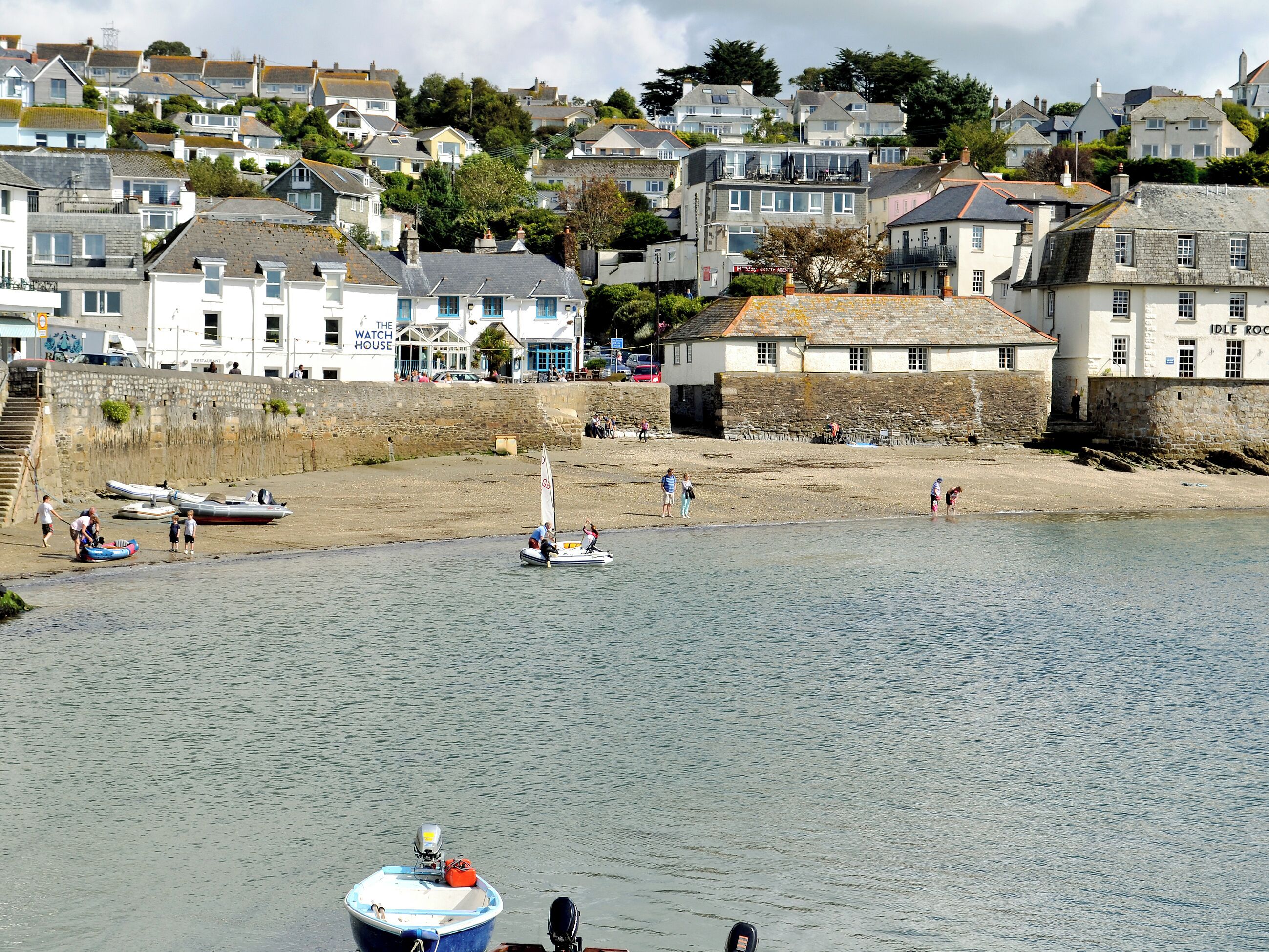 A coastal town with a sandy beach, boats, and residential buildings.