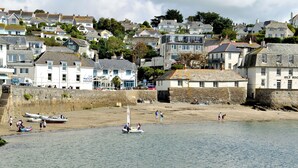 A coastal town with a sandy beach, boats, and buildings.
