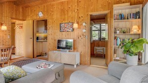 En mysig inredning med träpanel, TV, sittgrupp, bokhylla och en plats för måltider.