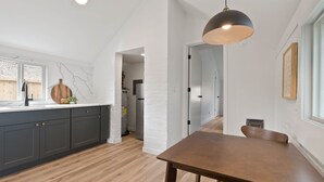 Eine moderne Küche mit dunklen Schränken, einem Holztisch und einer Pendelleuchte.